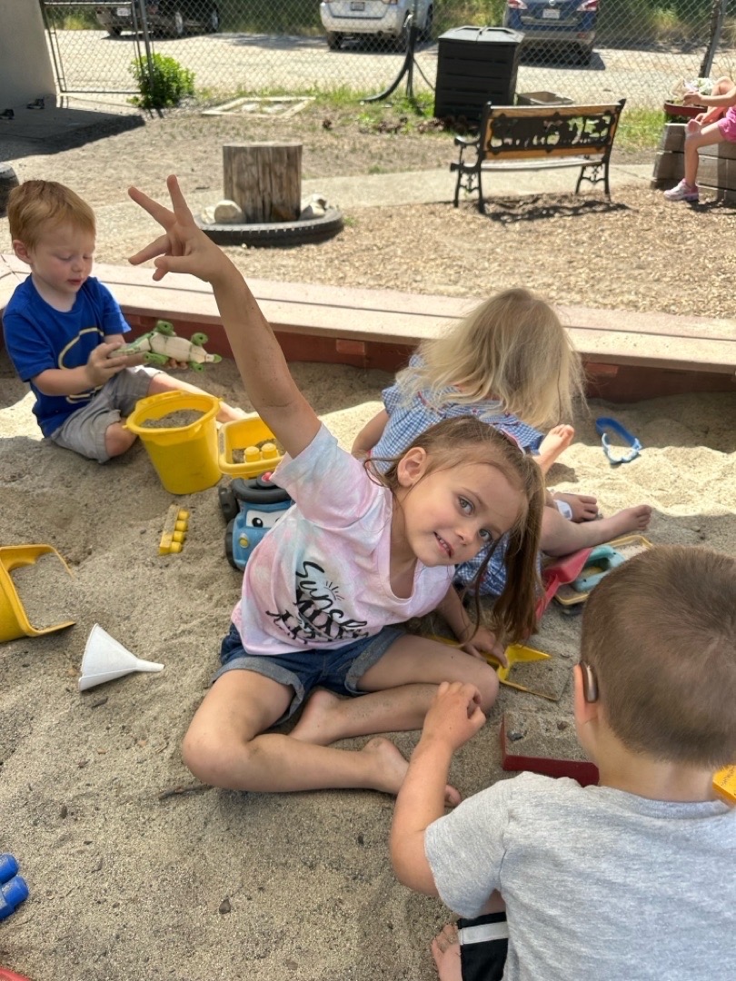Children playing in the sand at Mother Lode Mountain Tots preschool, one child smiling and flashing a peace sign</p>
<p>