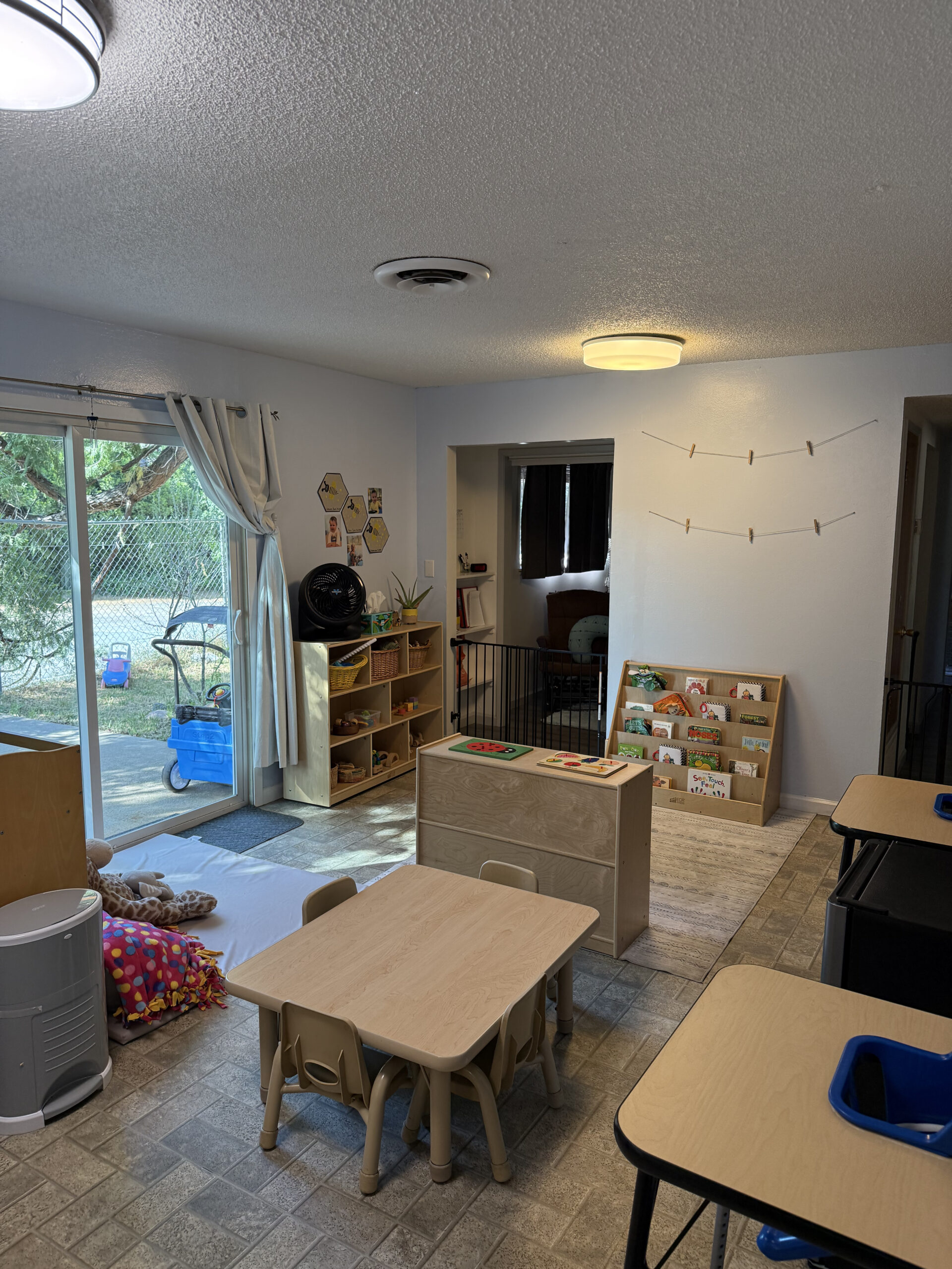 Infant and toddler classroom with floor beds, low shelves, child-sized furniture, and a cozy reading nook.</p>
<p>