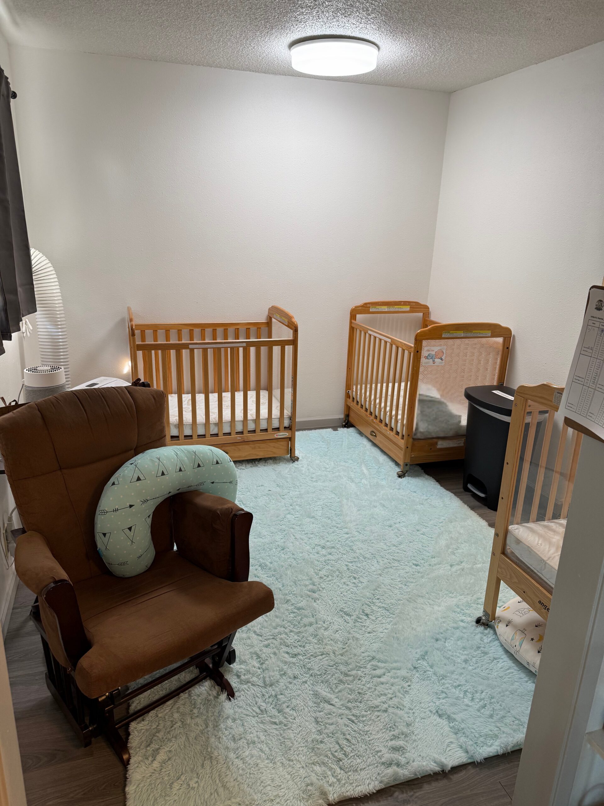 Peaceful infant nap area with cribs, soft lighting, a glider chair, and a plush rug.</p>
<p>